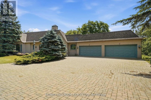 Close-up of the light brick exterior with light blue shutters and a paved walkway. - 18381 Mccowan Road, East Gwillimbury