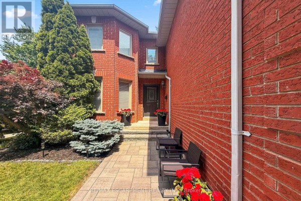 Pathway leading to the front entrance of a red brick house with two chairs. - 1839 Fellen Place, Mississauga
