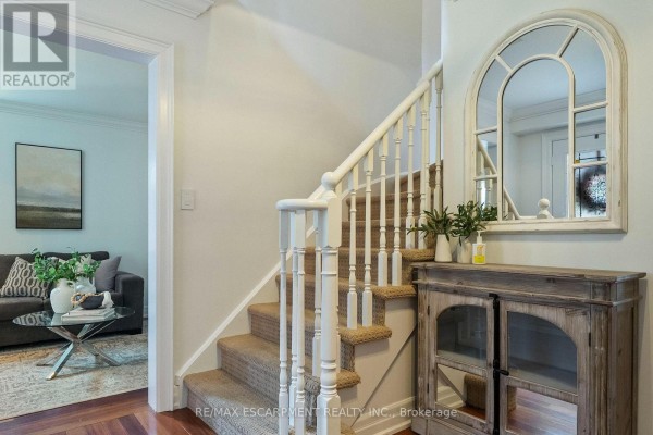 Staircase in the entrance hall with a rustic cabinet and arched mirror. - 1839 Fellen Place, Mississauga