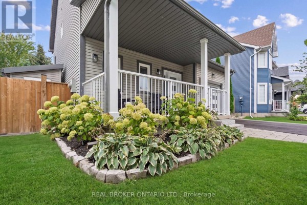 View of landscaping with hydrangeas and hostas in front of the covered porch of a grey house. - 184 Dunbar Street, Guelph/eramosa