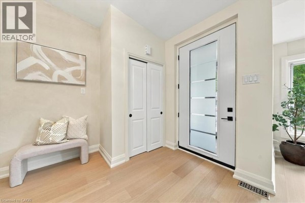Entrance hall with a frosted glass front door, bench seating, and double closet doors. - 184 Torresdale Avenue, North York