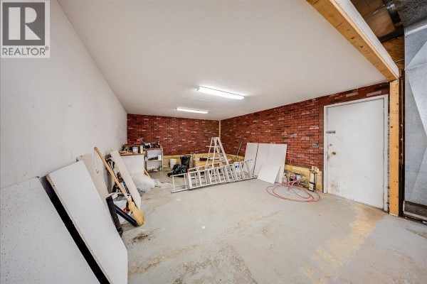Open commercial space with wooden walls, unfinished ceiling, metal shelving, and garage door. - 1846 First Street, Fruitvale