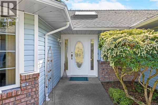 Front door of the light blue house with sidelights and a decorative oval glass insert. - 1848 Amelia Cres, Nanoose Bay