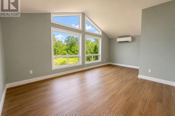 Interior room with light wood floors and a wide view through angled windows. - 1848 County Road 9, Greater Napanee