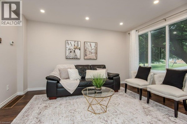 Living room furnished with a black leather sofa, two accent chairs, and a patterned rug. - 185 Cedarvale Crescent Unit# A, Waterloo
