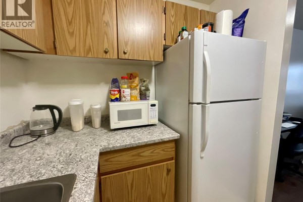 Close-up of kitchen appliances including a microwave and refrigerator in a compact layout - 185 Chamberlain Crescent Unit# 204, Tumbler Ridge
