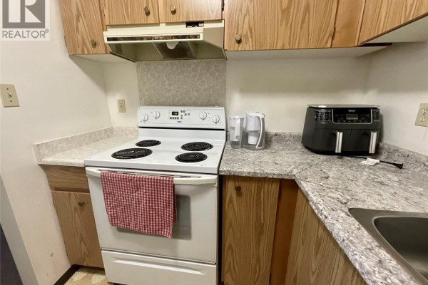 Stove and countertop in the kitchen with wooden cabinets and a red dish towel - 185 Chamberlain Crescent Unit# 204, Tumbler Ridge