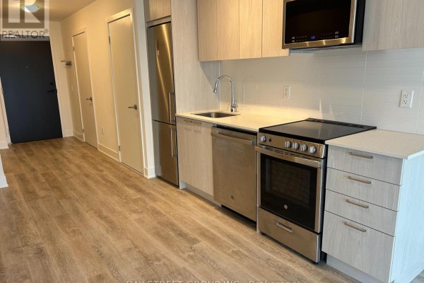 Open-concept living area with kitchen, large window, and light wood flooring - 612 - 185 Deerfield Drive, Newmarket