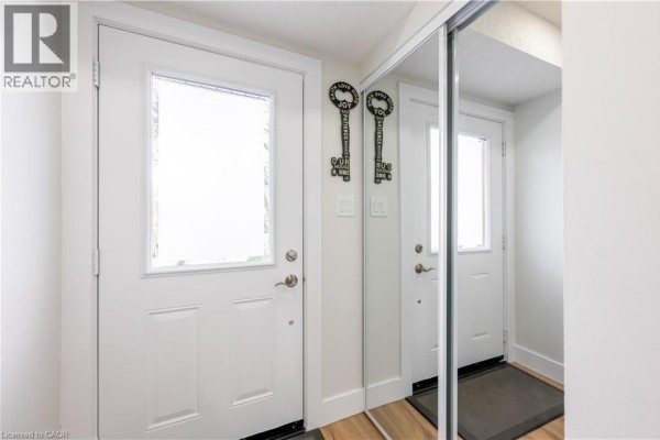 Entrance area with two white doors, a large mirror reflecting the entrance, and dark doormats. - 185 Highland Crescent Unit# 2, Kitchener