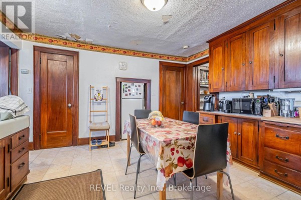 Kitchen with wooden cabinets, table, chairs, and a refrigerator. - 185 James Street, St  Catharines