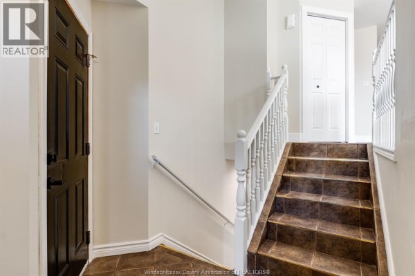 Interior staircase with brown tiled steps, white banister, and dark wood door. - 185 Marlborough Street East, Leamington