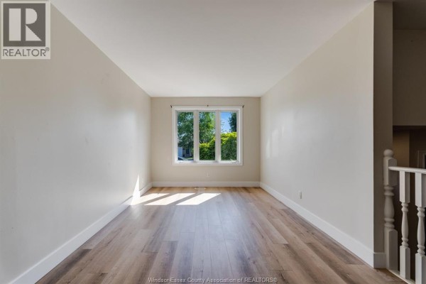 Empty living room with light wood floors, cream walls, and a large window. - 185 Marlborough Street East, Leamington