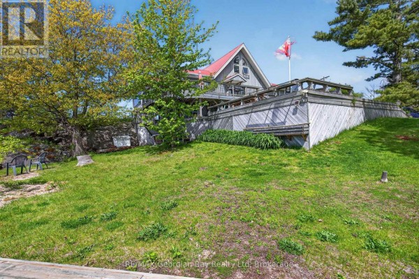 Exterior view of the house with a large deck and trees. - 185 Picnic Island Road, Georgian Bay