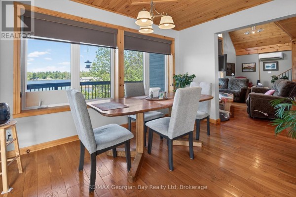 Dining area with wooden table and chairs, overlooking the water. - 185 Picnic Island Road, Georgian Bay