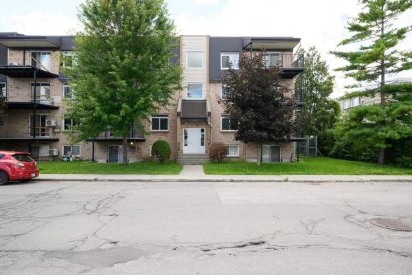 Side view of apartment building showing concrete steps and balconies with black railings. - 185 Rue Mutchmore, #8, Gatineau