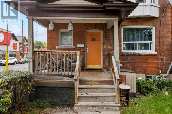 Close-up of the front porch with an orange door, wooden railings, and bicycles. - 185 Walmer Road, Toronto