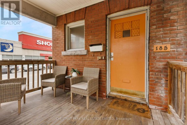 Wicker chairs and a small table on the wooden porch in front of an orange door. - 185 Walmer Road, Toronto