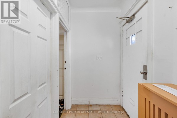 Interior hallway with white doors, white walls, and tiled flooring. - 185 Walmer Road, Toronto