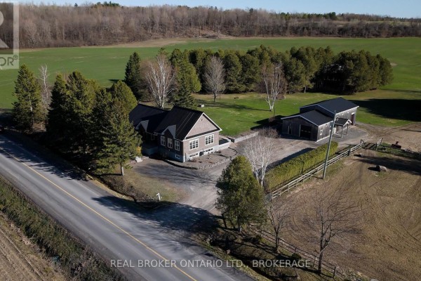 Side exterior of a two-story house with brown shingle siding and a dark metal roof. - 1850 Ridge Road W, Champlain