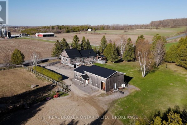 Rear exterior of a house with a deck and a view of expansive fields. - 1850 Ridge Road W, Champlain