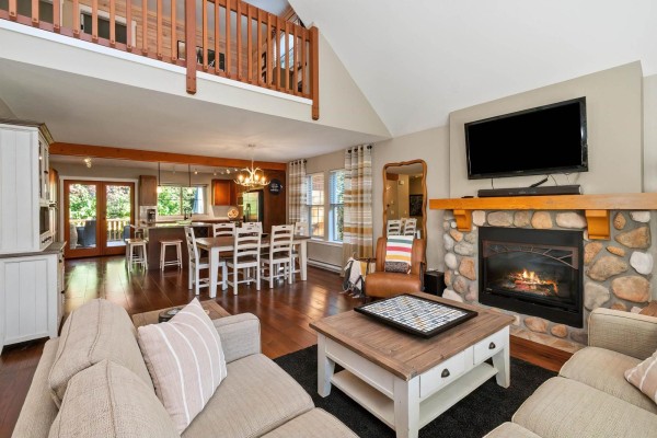 Living room with a stone fireplace, television, sofa, and open-concept dining area. - 1852 Ravenwood Trail, Cultus Lake South, Lindell Beach