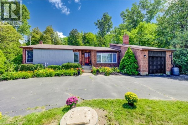 Front exterior of a single-story brick house with a garage and manicured garden. - 1853 Highway 24 S, Cambridge