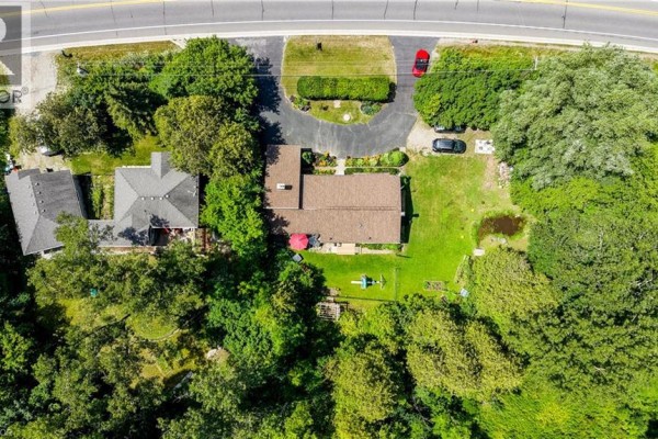 Overhead drone view of the house, backyard, and neighboring property nestled in trees. - 1853 Highway 24 S, Cambridge