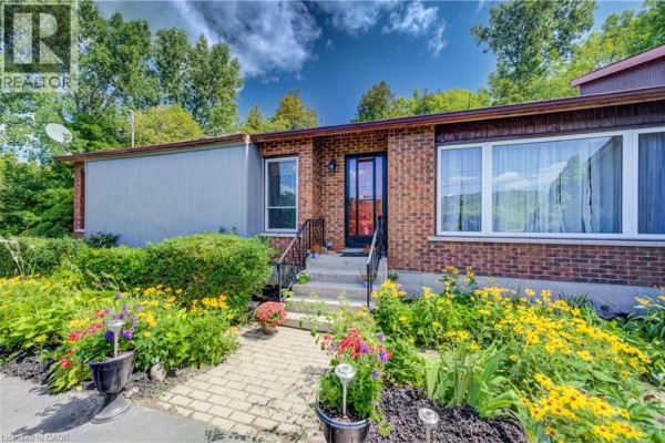 Front entrance of the brick house with a stone walkway and colorful flower beds. - 1853 Highway 24 S, Cambridge