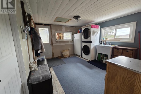 Small bathroom with a vanity, toilet, round mirror, blue walls, and patterned floor tiles. - 18540 Country Harbour  Hwy 316 Highway, Country Harbour