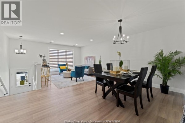 Open-concept living and dining area with light wood floors, contemporary furniture, and decorative plants. - 1855 Meldrum Road Unit# 1, Windsor