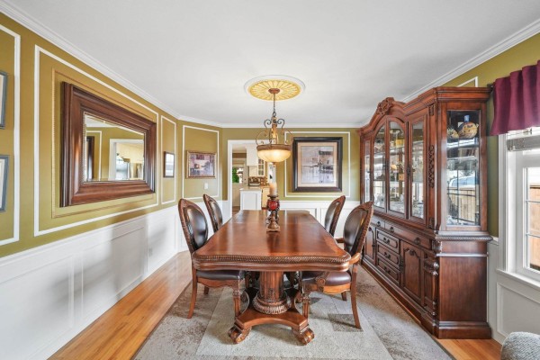 Formal dining room with a large wooden table, leather chairs, and a wooden buffet cabinet. - 18555 57 Avenue, Surrey