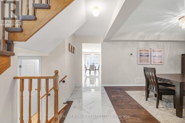 Upstairs landing with a curved staircase, hardwood floors, and doorways to bedrooms and a living area. - 1856 Rosebank Road, Pickering