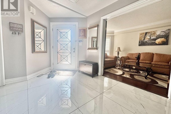 Foyer with white marble tile floors, decorative front door, two mirrors, and a doorway to the living room. - 186 Fernforest Drive, Brampton