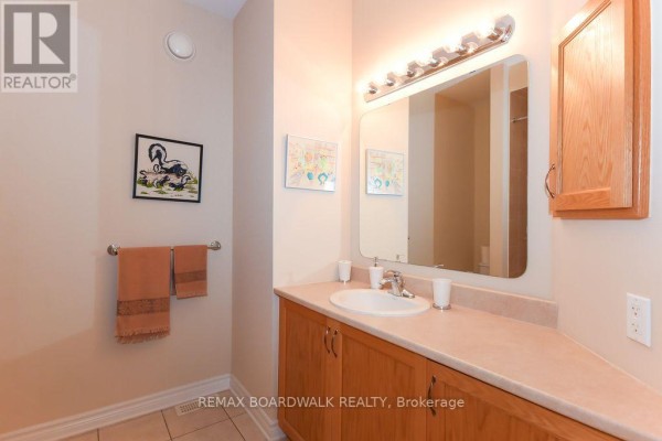 Bathroom with single vanity, wood cabinets, large mirror, and tiled floor - 1861 Mickelberry Crescent, Ottawa