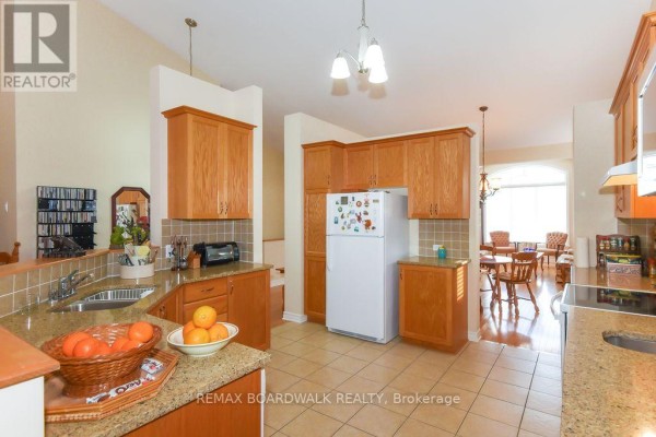 Open concept kitchen with wood cabinets, granite counters, tile backsplash, dining area - 1861 Mickelberry Crescent Ottawa