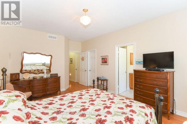 Bedroom with hardwood floors, dresser, mirror, and TV - 1861 Mickelberry Crescent, Ottawa