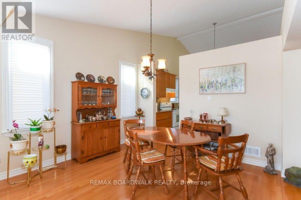 Dining room with hardwood floors, wooden table, hutch, chandelier, and view to kitchen - 1861 Mickelberry Crescent Ottawa