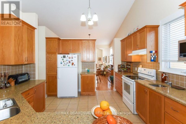 Kitchen with wood cabinets, granite counters, white appliances, vaulted ceiling - 1861 Mickelberry Crescent, Ottawa