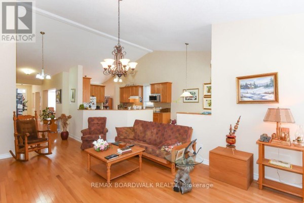 Open-concept living room with hardwood floors, vaulted ceiling, kitchen, and dining area - 1861 Mickelberry Crescent, Ottawa