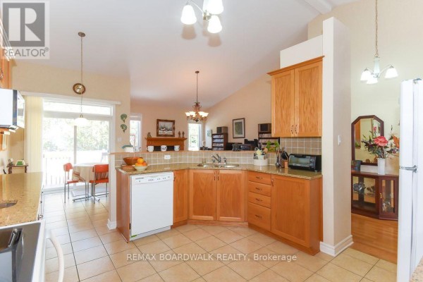 Kitchen with wood cabinets, granite counters, tile floors, and dishwasher - 1861 Mickelberry Crescent, Ottawa