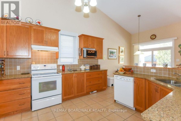 Kitchen with wood cabinets, granite counters, tile backsplash, white appliances - 1861 Mickelberry Crescent, Ottawa