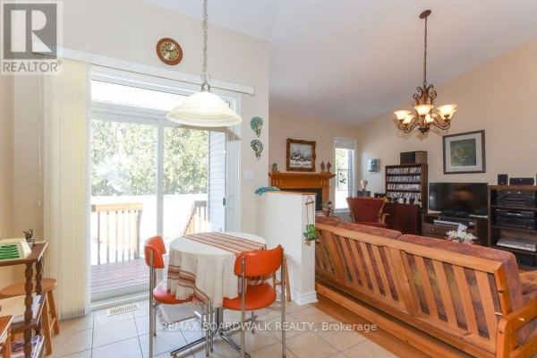 Open concept dining & living room with fireplace, tiled floor, sliding door to deck - 1861 Mickelberry Crescent, Ottawa