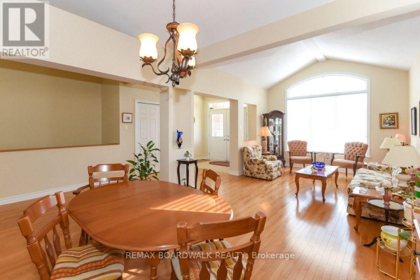 Open concept dining & living room with vaulted ceiling, hardwood floors, arched window - 1861 Mickelberry Crescent, Ottawa