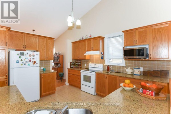 Kitchen with wood cabinets, granite counters, tile floor, white appliances, microwave, island - 1861 Mickelberry Crescent, Ottawa