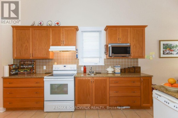 Kitchen with wood cabinets, granite counters, white appliances, tiled floor - 1861 Mickelberry Crescent Ottawa