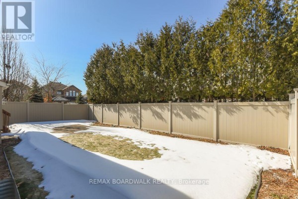 Backyard with modern fence, evergreen trees, and partial snow cover - 1861 Mickelberry Crescent, Ottawa
