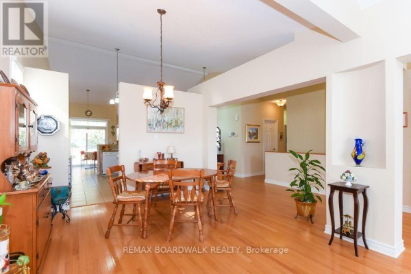 Dining room with hardwood floors, chandelier, and adjacent kitchen - 1861 Mickelberry Crescent, Ottawa