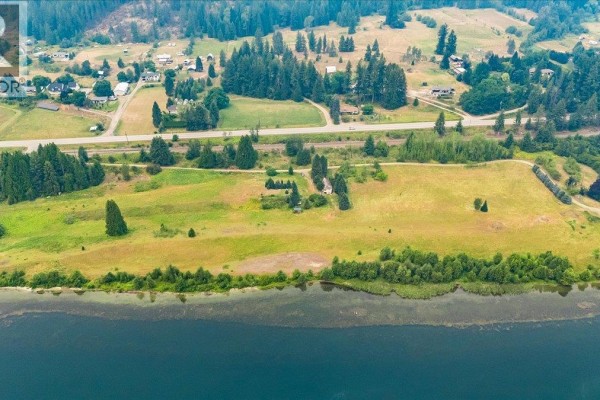 Aerial view looking down a winding river with a highway, scattered homes, and forested mountains. - 1864 Highway 3a, Castlegar