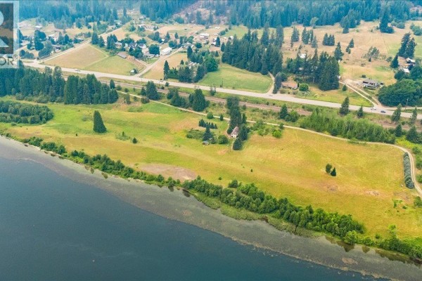 Aerial view of a long river valley with a highway, scattered houses, and evergreen forests. - 1864 Highway 3a, Castlegar