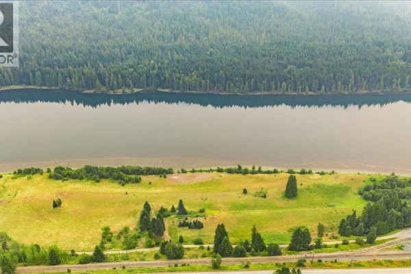 Aerial view of a river winding through a valley with a highway and homes nestled among trees. - 1864 Highway 3a, Castlegar